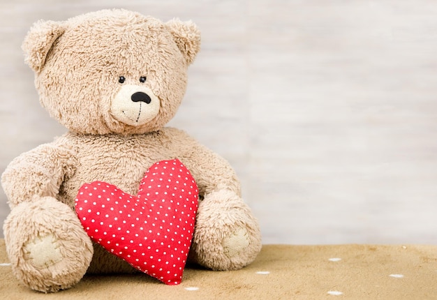 Un oso de peluche y un corazón rojo El concepto de juego amor felicidad alegría y celebración