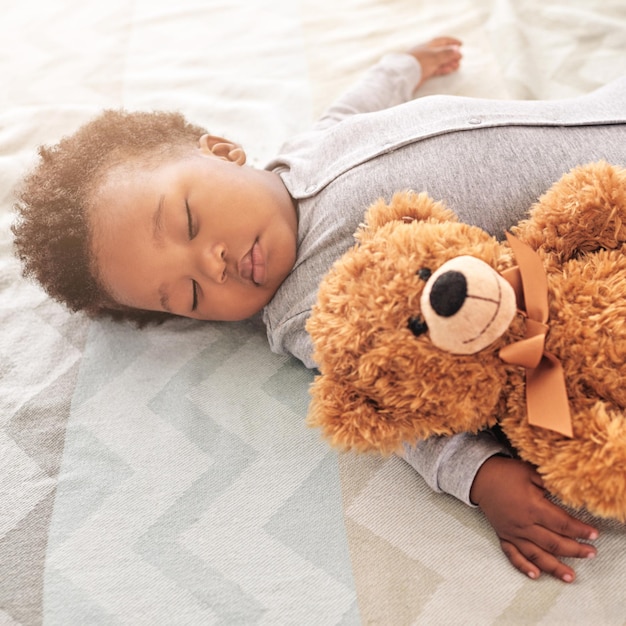 Oso de peluche durmiendo y lindo con el bebé en el dormitorio para un desarrollo e inocencia sin preocupaciones Soñando relajado y cómodo con un bebé africano y un juguete en casa para descansar por la mañana y acostarse