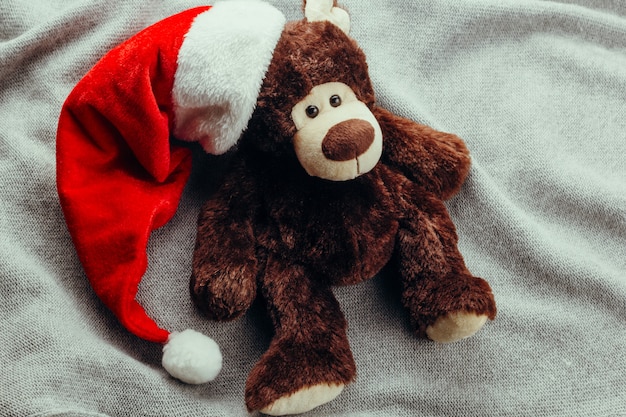 Oso de peluche en gorro de santa claus sobre un fondo de punto