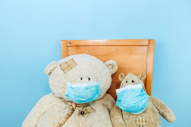 Oso de peluche y el hipopótamo en una máscara médica en una pared azul. Concepto de pandemia de coronavirus Covid-19 2019-20.