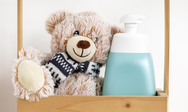 Un oso de peluche junto a una botella de jabón.