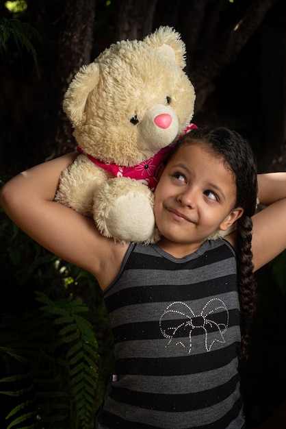 Oso de peluche, niño brasileño jugando con mucho cariño con su osito de peluche, enfoque selectivo.