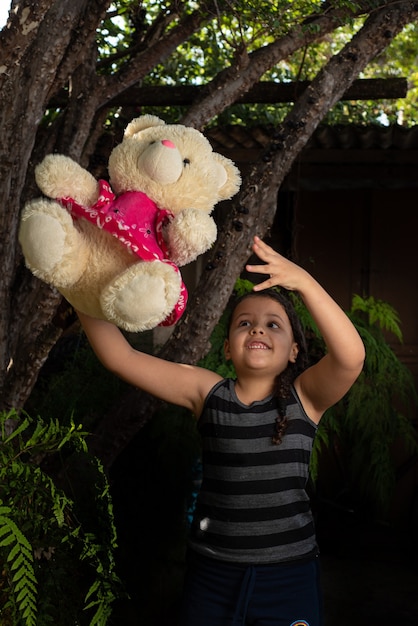 Foto oso de peluche, niño brasileño jugando con mucho cariño con su osito de peluche, enfoque selectivo.