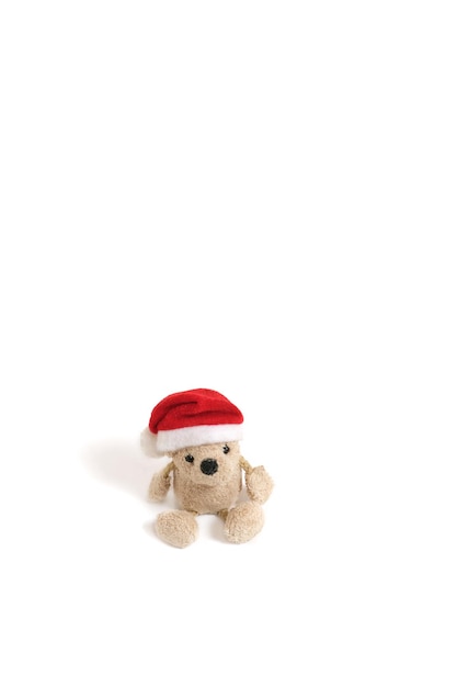 Oso de peluche relleno con un sombrero de santa claus sobre un fondo  blanco.