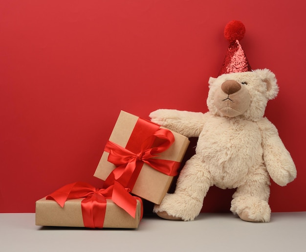 un oso de peluche en un sombrero festivo rojo sostiene una hoja de papel rosa