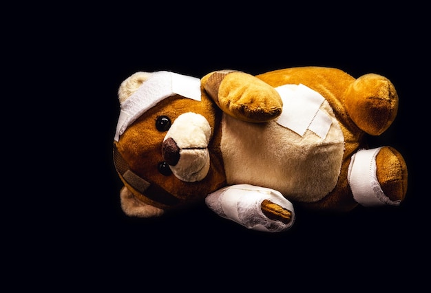 Oso de peluche vendado con vendajes y tirita tirada en el suelo concepto de abuso infantil o imagen de violencia que representa la violencia doméstica