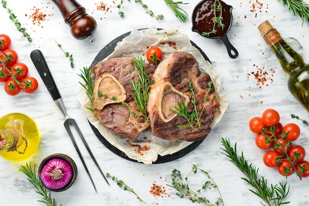 Osso buco cozido Pernil de vitela com especiarias e legumes sobre fundo branco de madeira Vista superior plana