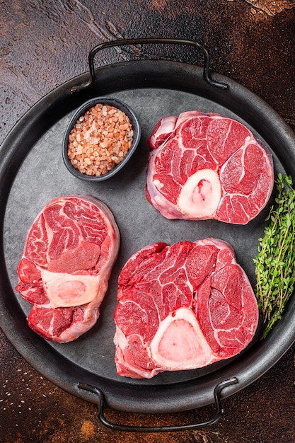 Ossobuco cru Carne de pernil de vitela Ossobuco em tabuleiro de aço Fundo escuro Vista de cima