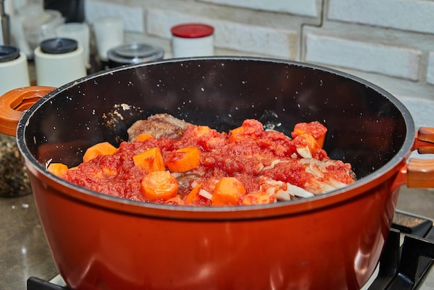 Ossobuco hierve a fuego lento en una cacerola con zanahorias y salsa