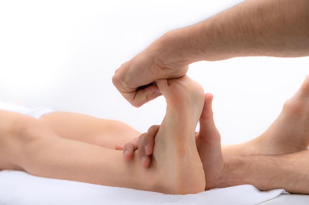 Foto osteópata doctor hands hace tratamiento de osteopatía en el pie del paciente concepto de cuidado corporal fondo blanco enfoque selectivo