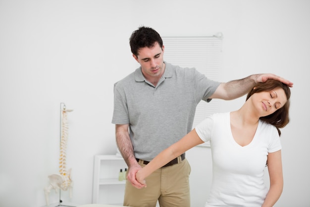 Osteópata estirando el brazo de una mujer en una sala médica