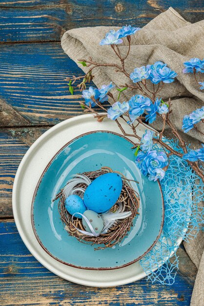 Foto oster-tischgestaltung mit eiern, vogel-nest und blühendem zweig