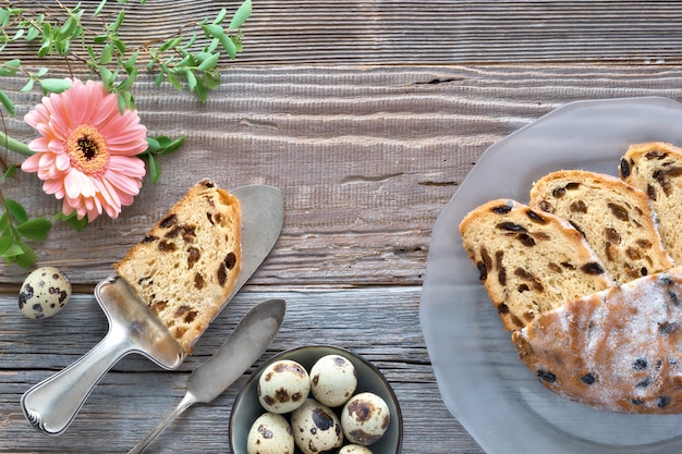 Osterbrot. Draufsicht des traditionellen fruty Brotes auf rustikalem Holz mit frischen Blättern und Wachteleiern.