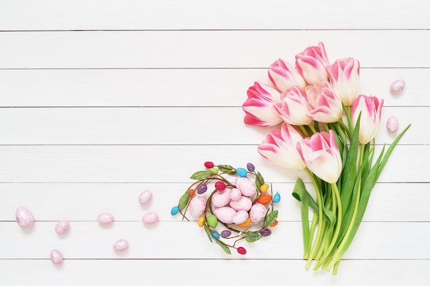 Osterdekoration. Dekorative Ostereier und rosa Tulpen auf weißer Wand kopieren Raum, Draufsicht.