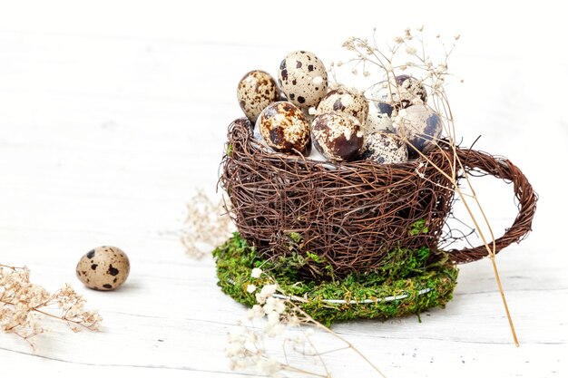 Osterdekoration mit Ei im Nestbecher auf weißem Holztisch