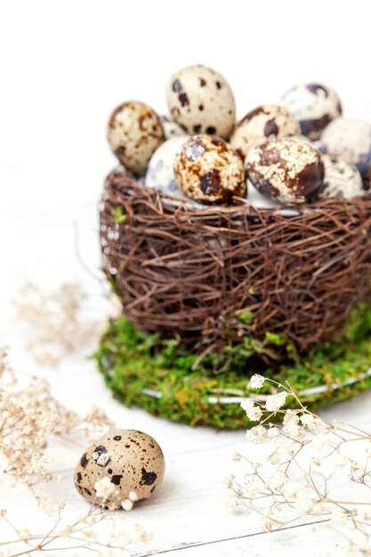 Osterdekoration mit Ei im Nestbecher auf weißem Holztisch