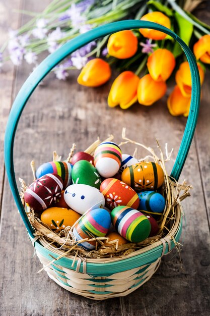 Osterei in einem Korb und in den Tulpen auf Holztisch