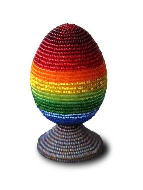 Osterei verziert mit bunten Perlen des Regenbogens auf dem Stand lokalisiert auf weißem Hintergrund