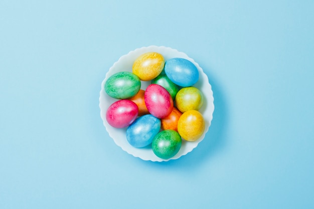 Ostereier auf einem Teller auf blauem Hintergrund. Konzept, Ostern zu feiern. Flache Lage, Draufsicht