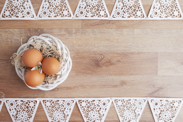 Ostereier im Nest auf rustikalem Holztisch, Feiertagshintergrund für Ihre Dekoration. Frühlings- und Osterferienkonzept mit Kopierraum.