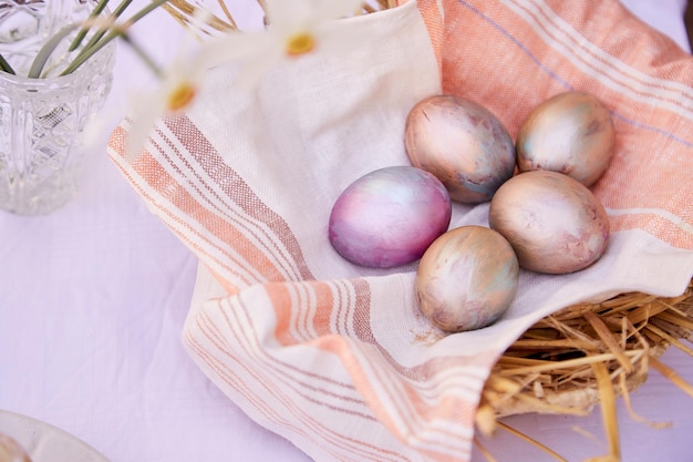 Ostereier im Weidenstrohkorb Veri peri und orangefarbene bunte Eier und Narzissenblumen Kopierraum von oben