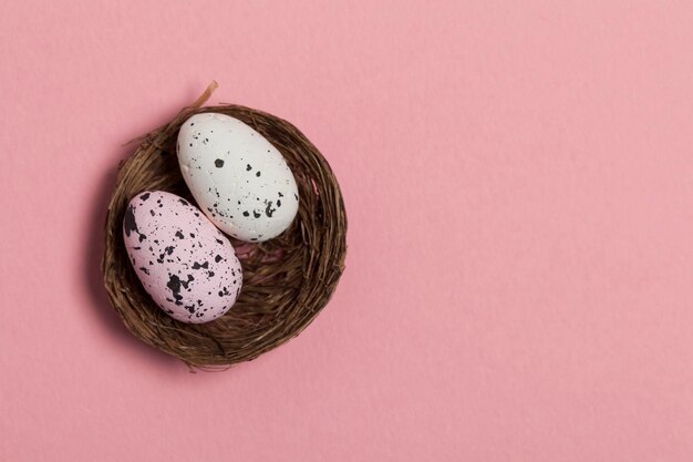 Ostereier in einem Nest auf pastellrosa Hintergrund