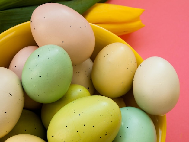 Ostereier in gelber Schüssel und frischen Tulpen.