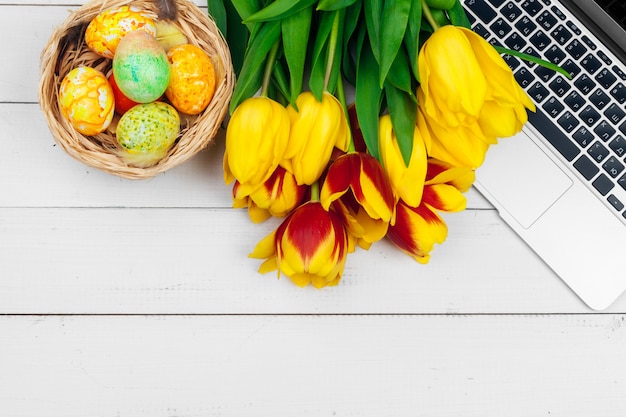 Ostereier, Laptop und Strauß Tulpen.