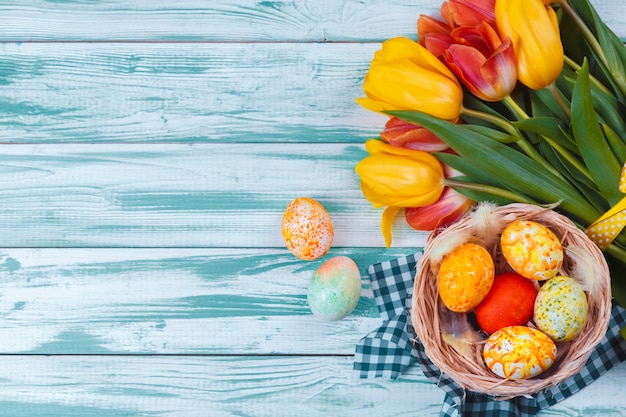 Ostereier mit Tulpen auf blauem hölzernem