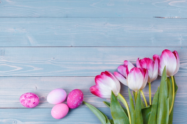 Ostereier mit Tulpen auf blauem hölzernem