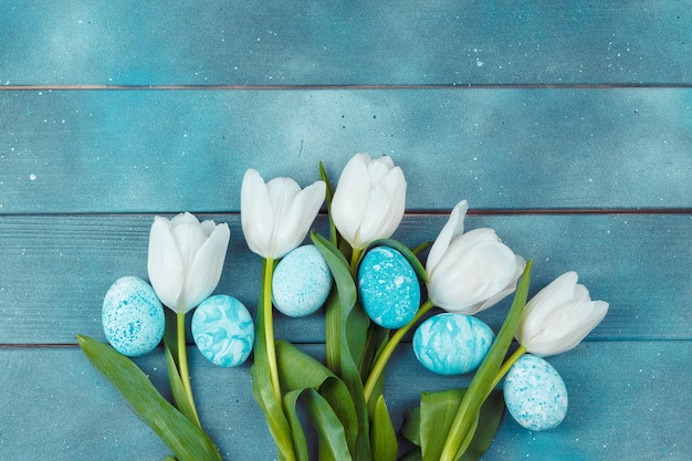 Ostereier mit Tulpen auf blauem hölzernem