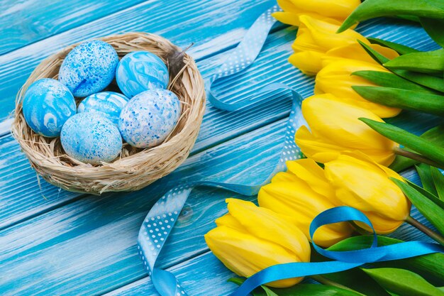 Ostereier mit Tulpen auf hölzernem Brett, Ostern-Feiertag. Exemplar für Text