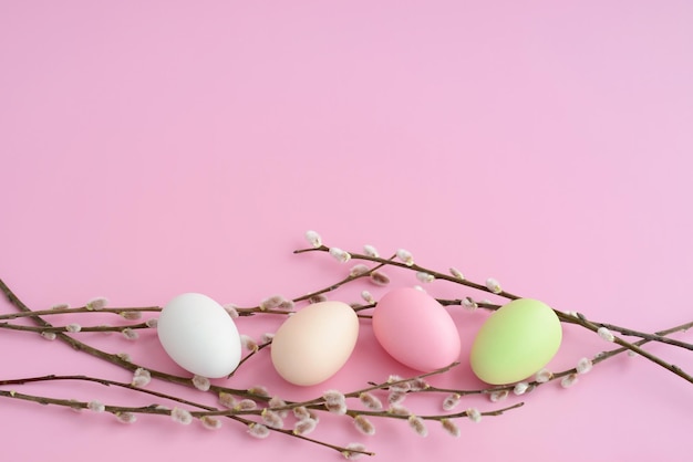 Ostereier mit Weidenkätzchen auf rosafarbenem Tisch Weidenkätzchenbündel und farbige Eier auf rosafarbenem Hintergrund