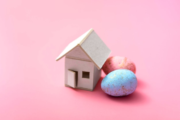 Ostereier und Haus auf einem rosa Hintergrund. Familienurlaubskonzept. Grußkartenvorlage. Mit Kopienraum. Nahansicht