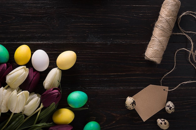 Ostereier und Tulpen auf dunklen Holzbohlen