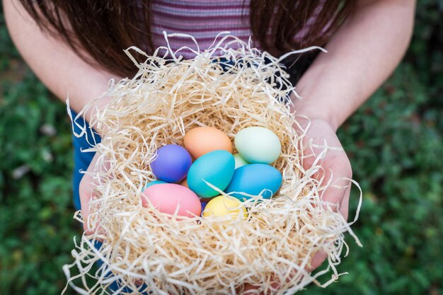 Ostereiersuchmädchen, das ein Nest mit farbigen Eiern fängt