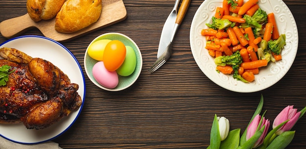 Osteressen auf dunklem rustikalem Tisch pastellfarbene Eier Brathähnchen-Gemüse-Brötchen