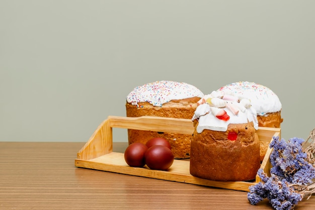 Osterferien-Food-Konzept Hausgemachter Osterkuchen mit weißem Zuckerguss, Geleebonbons, süßes Pulver, verziert mit farbigen Eiern, Blumen, Blüten auf Holzhintergrund mit Kopierbereich. Selektiver Fokus