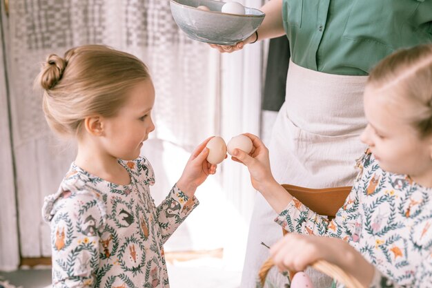 Foto osterferienzeit in der frühlingssaison glückliche familie ehrliche kleine kinder schwestern mädchen zusammen mutter mutter haben spaß zu hause traditionelles fesseln oder dumping mit eiern religiöse tradition