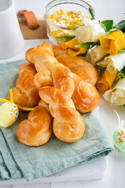 Osterfrühstück Holliday-Konzept Osterbrötchen mit Zimtbrötchen aus Hefeteig mit orangefarbener Glasur Osterschmuck farbige Eier auf weißem Frühlingshintergrund Osterholliday-Karte