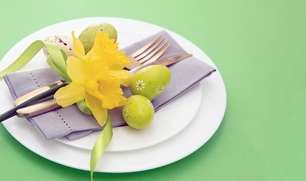 Ostergedeck Gelbe Frühlingsblumen-Serviette und goldenes Besteck auf weißen Tellern