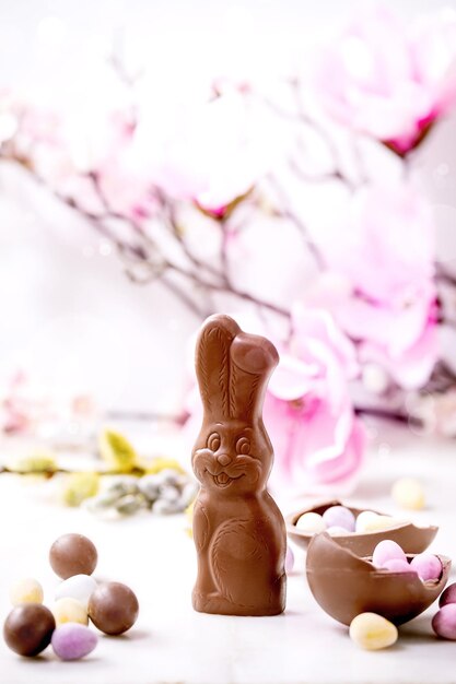 Ostergrußkarte mit Schokoladenbonbonkaninchen, Bonbons und Eiern, Frühlingsblütenzweige auf weißem Hintergrund. Ostern Leckereien