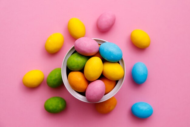 Osterhase. Frohes Osterferienhintergrundkonzept. Flaches gelegtes buntes Häschenei mit Zubehör zur Feier auf modernem rustikalem rosa Pastellpapier am Schreibtisch zu Hause.