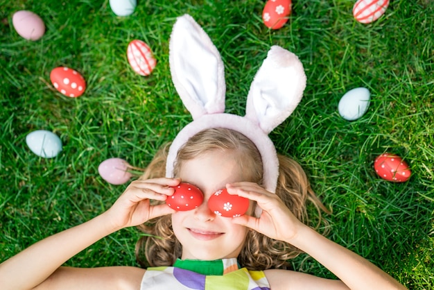 Osterhase. Kind, das Spaß im Freien hat. Kind, das mit Eiern auf grünem Gras spielt. Frühlingsferien-Konzept