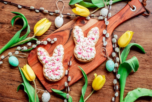 Foto osterhasen auf einem holzbrett mit ostereiern und blumen