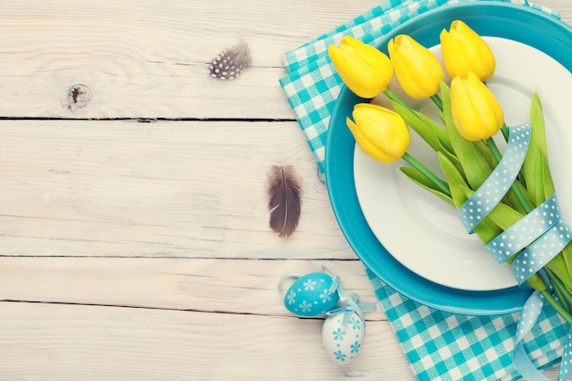 Osterhintergrund mit gelben Tulpen und bunten Eiern