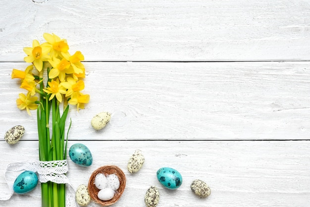 Osterhintergrund mit Ostereiern und Frühlingsblumen auf weißem Holztisch