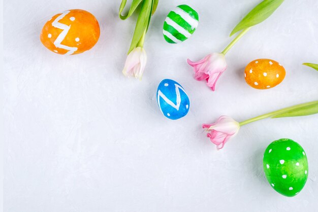 Osterkarte mit bunten Eiern und Frühlingsblumen Tulpen auf einem weißen Hintergrund