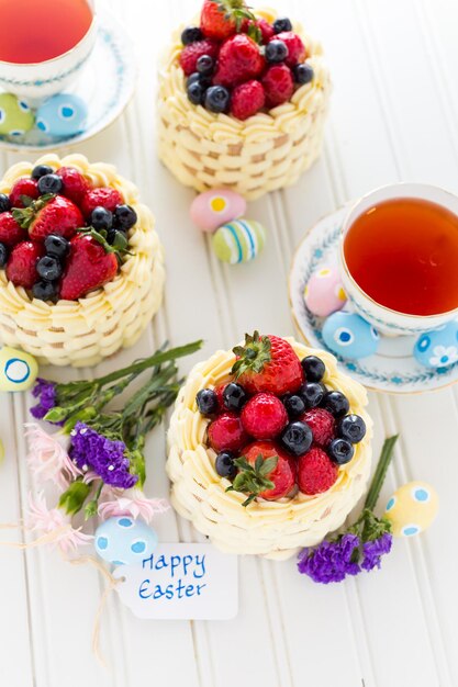 Osterkörbchen-Minikuchen mit glasiertem frischem Obst obenauf.