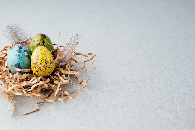 Osterkomposition mit bemalten Eiern in einem Nest auf grauem Hintergrund, Exemplar. Ostertradition, Hintergrund. Vorbereitung für die Feier von Ostern, kreatives Konzept.